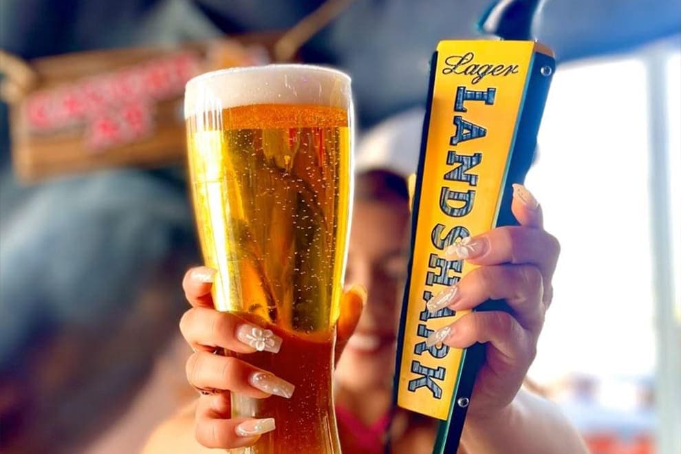 Server holding a draft beer next to a Land Shark tap handle at Cabo Joe's